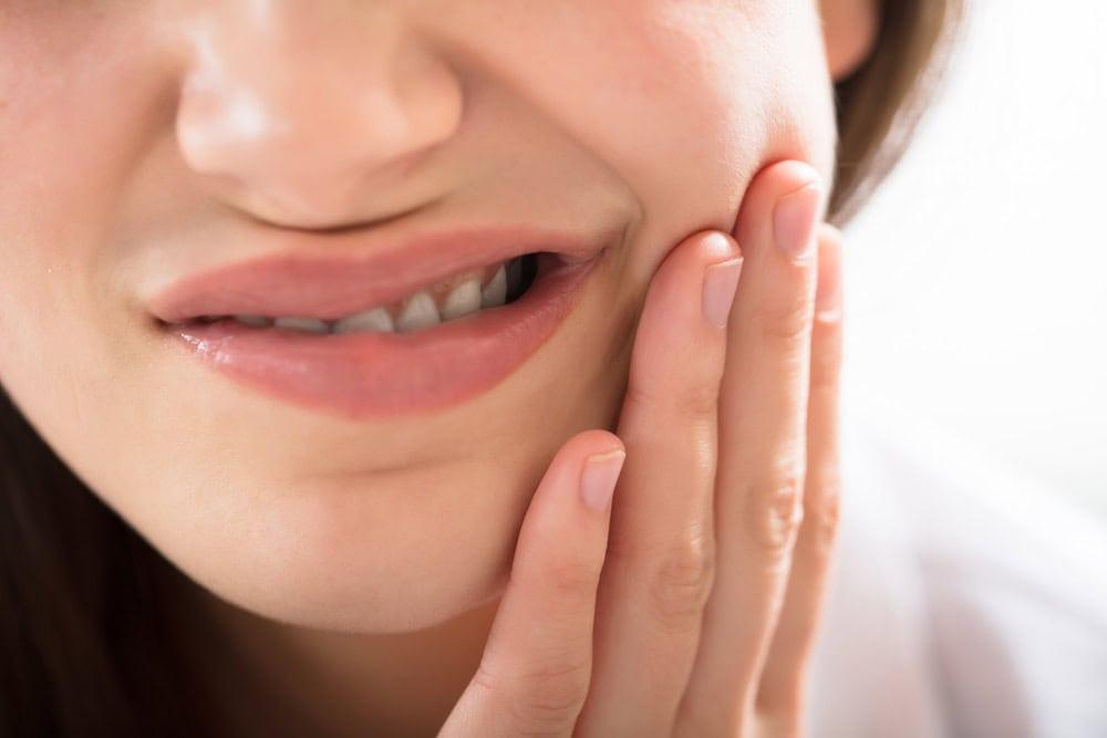 ผู้หญิงกำลังกุมแก้มปวดฟัน-มีอาการฟันผุ